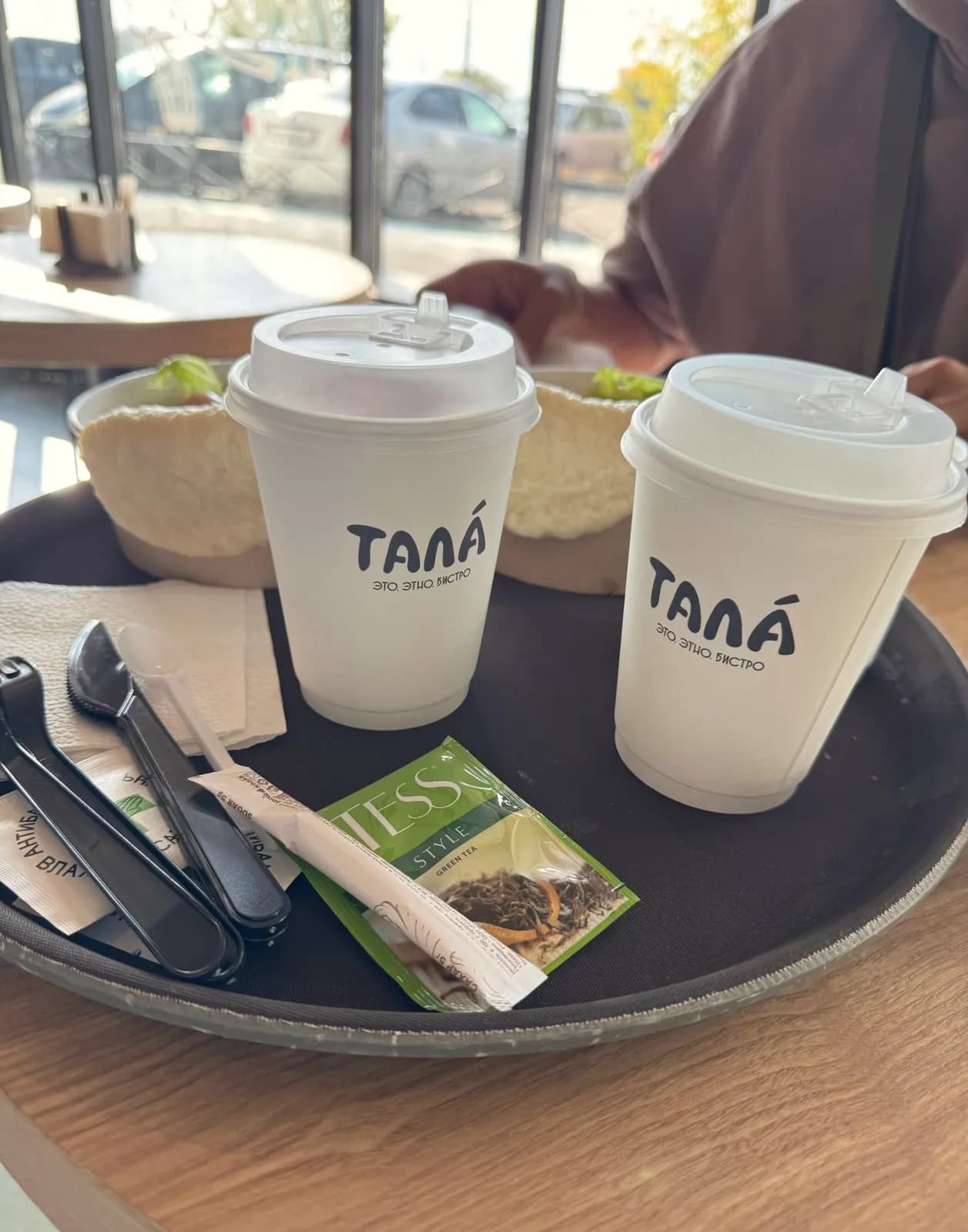 Два стакана с логотипом «Тала» на подносе у окна